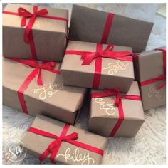 six wrapped presents with red ribbon on them sitting on a white carpeted floor next to each other