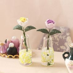 three vases with flowers in them sitting on a table next to other decorative items