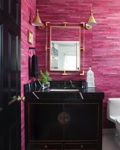 a bathroom with pink walls and black cabinets