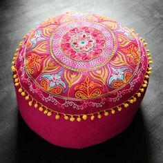 a pink and yellow round ottoman with tassels