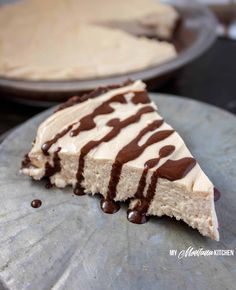 a slice of cheesecake with chocolate drizzled on it and another pie in the background