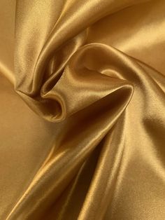 "60\" wide luxurious gold charmeuse satin fabric is a beautiful lightweight soft and smooth with a silk like appearance and feel, drapes nicely and made with 100% polyester fibers. Great for party decor, backdrops, blouses, apparel, lingerie, lining, chair sashes, curtains, tablecloths, linens, overlays, and much more. Sold by the yard continuous up to the length of the roll. For instance an order of 1 yard (Qty=1) is 60\" x 36''. Order of 3 yards (Qty=3) is 60\" x 108''. Color can vary by dye l Colored Burlap, Lame Fabric, Lace Bag, Charmeuse Fabric, Gold Curtains, Monks Cloth, Jute Tote Bags, Chair Sashes, Burlap Lace