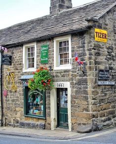 an old stone building with flowers growing out of it's windows and on the outside