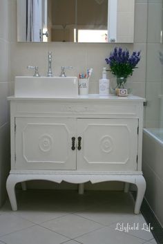 a white sink sitting under a bathroom mirror