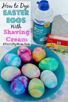 some colorful eggs are in a blue bowl on a table next to a bottle of glue