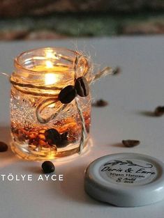 a jar filled with coffee beans sitting on top of a table next to a candle