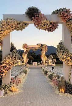 an outdoor wedding setup with flowers and candles on the aisle, surrounded by greenery