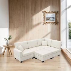 a large white sectional sofa sitting on top of a hard wood floored living room