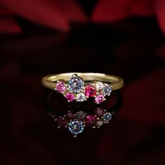 three stone ring sitting on top of a black surface with red flowers in the background