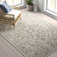 a living room area with a chair and rug on the floor next to a window