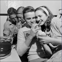 black and white photograph of three women eating ice cream sandwiches with friends in the background