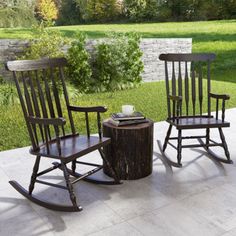 two wooden rocking chairs sitting on top of a cement floor next to a tree stump