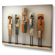 four wooden sculptures are lined up against the wall