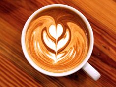 a cappuccino on a wooden table with a leaf in the foaming