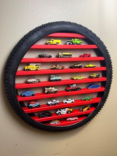 a wall mounted toy car display with red shelves and black tire rim on the wall