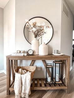 a wooden table topped with vases filled with flowers next to a wall mounted clock