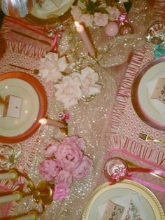 the table is set with pink flowers and plates