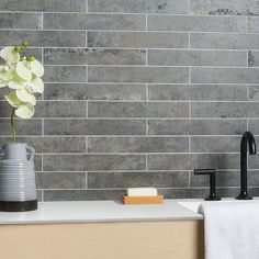 a vase with white flowers in it sitting on a counter next to a faucet