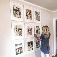 a woman standing in front of a wall with pictures hanging on the side of it