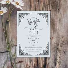 a white wedding card with a black pig on it and daisies in the foreground