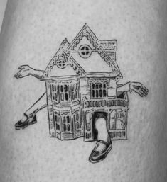 a black and white drawing of a house on the back of a woman's thigh