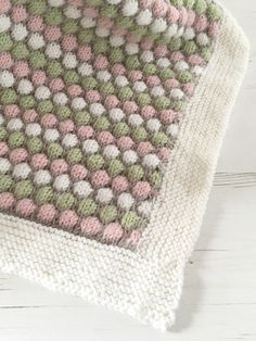 a crocheted blanket laying on top of a white wooden floor