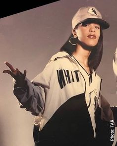 a woman in a baseball uniform holding her hands up