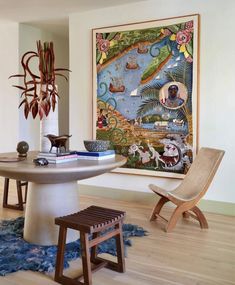 a table with two chairs and a painting on the wall