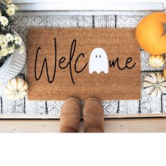 someone is standing in front of a welcome mat with a ghost on it and pumpkins