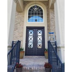 the front entrance to a home with two potted plants on either side of the door