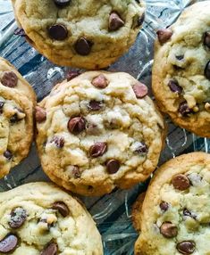 several chocolate chip cookies sitting on top of a glass plate with one cookie in the middle