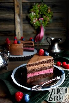 a slice of chocolate cake on a plate with raspberries