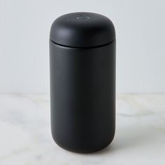 a black canister sitting on top of a white counter