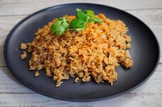 a black plate topped with rice and garnished with cilantro on top