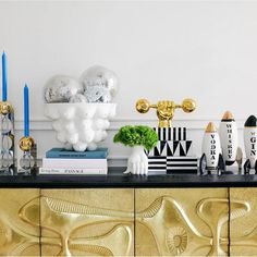 a black and gold sideboard with some decorations on top of it, including candles