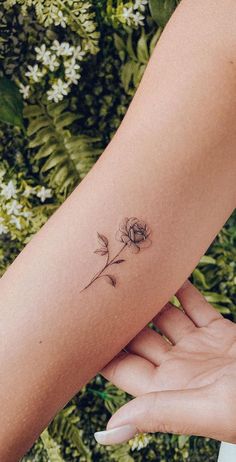 a woman's arm with a small flower tattoo on the left side of her arm