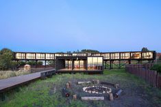 a fire pit sitting in the middle of a grass covered field next to a building