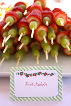 fruit kabobs are arranged on skewers with a place card in the middle