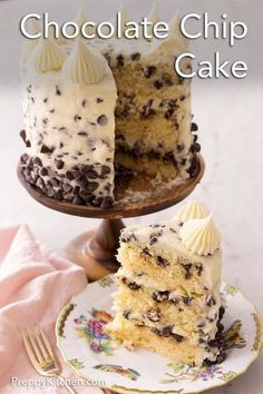 a chocolate chip cake on a plate with a slice missing from it and the rest of the cake in the background