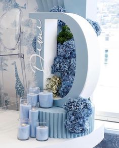 a table topped with blue flowers and candles next to a large letter that says love