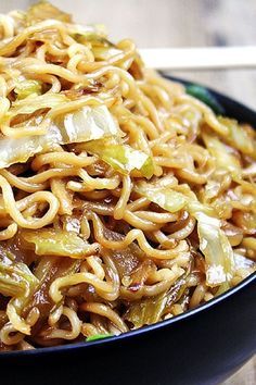 a black bowl filled with noodles and vegetables