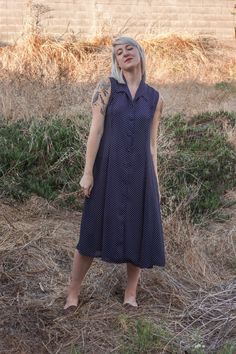 "this gorgeous vintage dress appears to be 50's inspired, with 70's boho flair. a dark navy blue with  white polka dots, collar, and white buttons down the entire front, the dress is also a bit sheer (see photos). will look nice with a slip underneath, and even with a belt to cinch in the waist (not pictured). appears to be in wonderful conditions despite its age, and would look gorgeous with some brown espadrille sandals or vintage heels - or make it casual, and pair it with some vintage lace-u Vintage Style Summer Midi Dresses, Vintage Style Midi Length Summer Dresses, Collared Polka Dot Dresses With Buttons, Polka Dot Collared Dress With Buttons, 1950s Style Polka Dot Dresses For Spring, Vintage Fashion Polka Dot Dresses, 1950s Style Fitted Dress With Buttons, Vintage Fashion Summer Midi Dress, Spring Polka Dot Vintage Dress