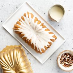 a white plate topped with a bundt cake covered in icing next to a cup of milk