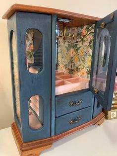 a doll house with blue furniture and floral wallpaper on the walls, including an open door