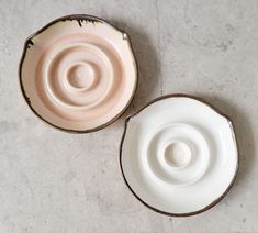 two white bowls sitting next to each other on top of a gray tablecloth covered floor