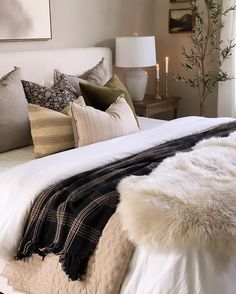 a white bed topped with lots of pillows and blankets