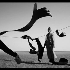 a woman standing on top of a sandy beach next to clothes hanging from a line