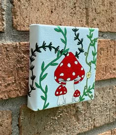 a painting on the side of a brick wall with mushrooms and leaves painted on it