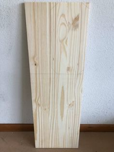 a piece of wood sitting on top of a wooden floor next to a white wall