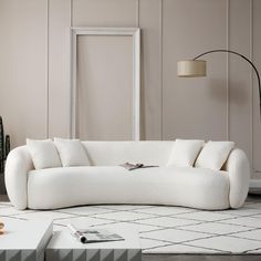 a white couch sitting on top of a rug next to a lamp and table in a living room